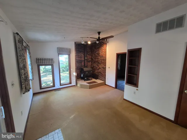 a view of a room with large windows and a ceiling fan