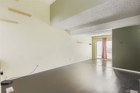 an empty room with wooden floor and windows with curtains