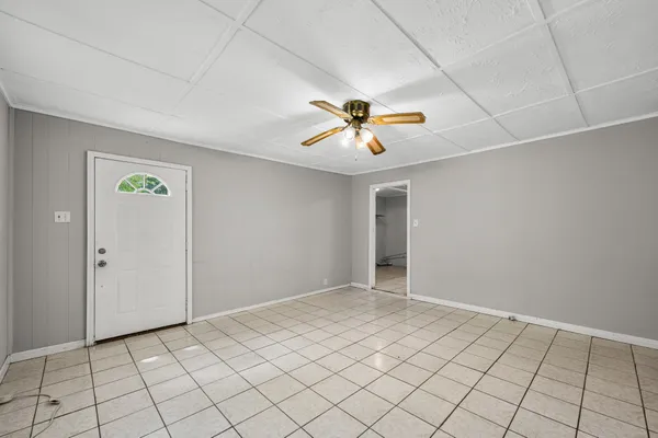 an empty room with chandelier fan and windows