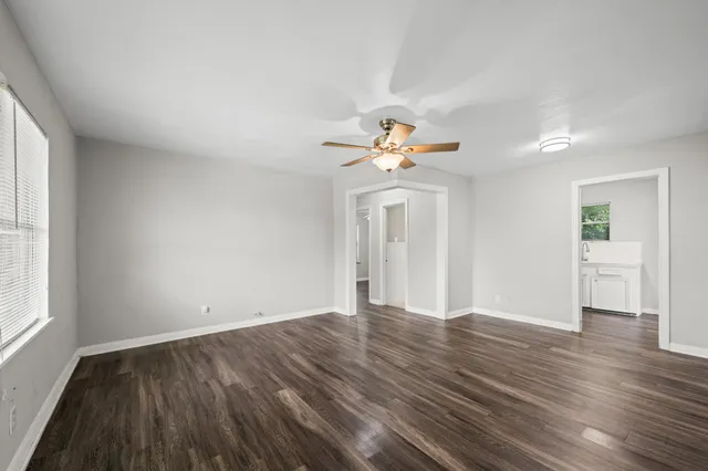 an empty room with wooden floor and windows