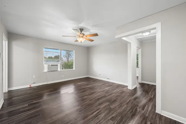 an empty room with wooden floor and windows