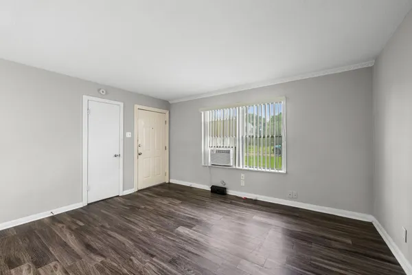 a view of an empty room with wooden floor and a window