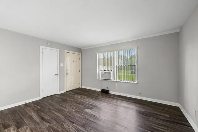 a view of an empty room with wooden floor and a window