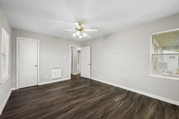 a view of an empty room with wooden floor and a window