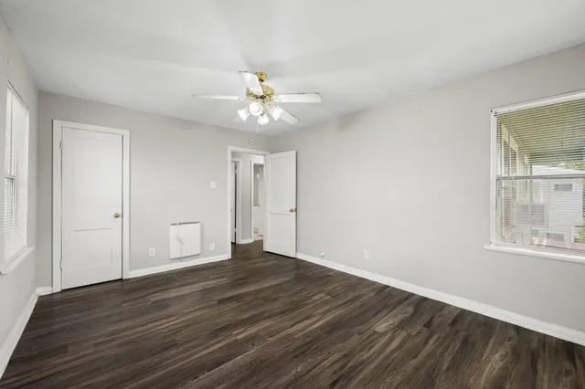 a view of an empty room with wooden floor and a window