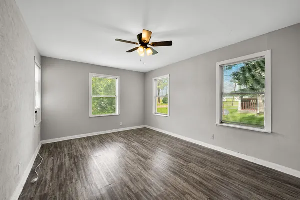 an empty room with windows and ceiling fan
