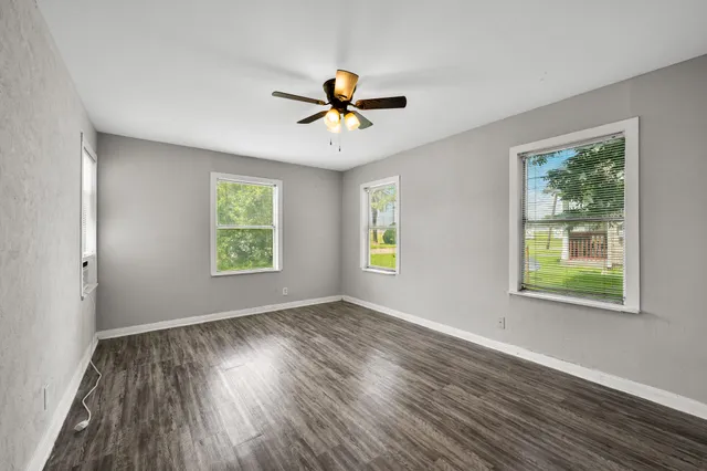 an empty room with windows and ceiling fan
