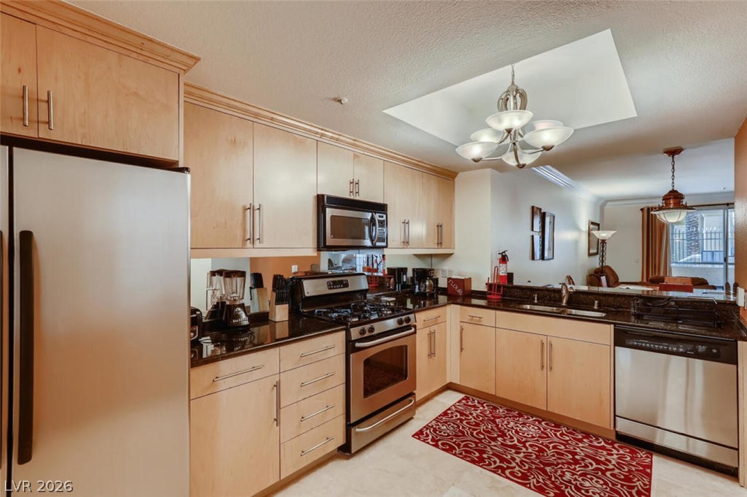 210 East Flamingo Road, Unit 137 Las Vegas, NV 89169 - Photo 4 of 32 A well-lit kitchen with sleek wooden cabinetry and modern stainless steel appliances.