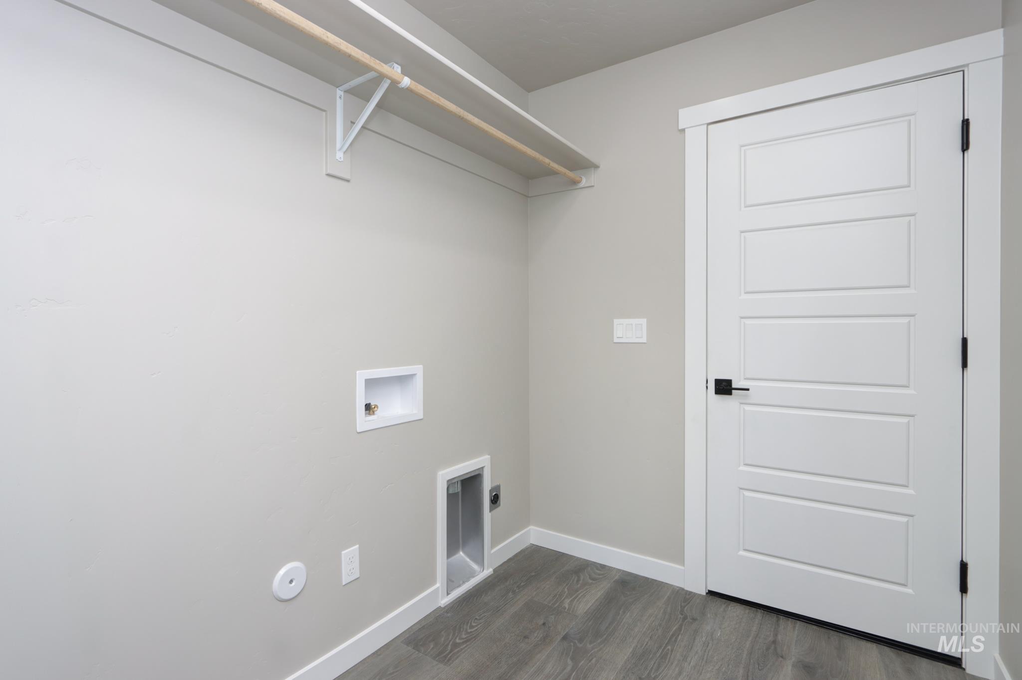 848 North 5th Street Nyssa, OR 97913 - Photo 37 of 49 Dedicated laundry area featuring modern gray wood-finish flooring, a contemporary five-panel door with matte black hardware, and an overhead clothes rod with shelving