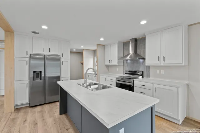 a kitchen with stainless steel appliances white cabinets and a stove top oven