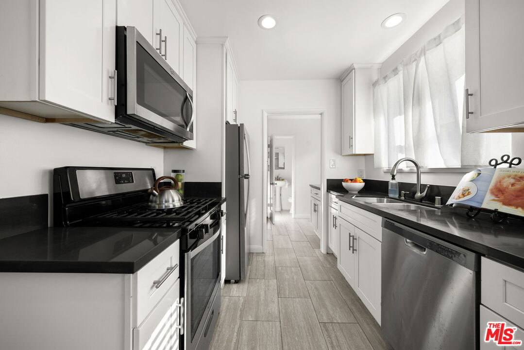 3770 Buckingham Road Los Angeles, CA 90016 - Photo 6 of 19 a kitchen with stainless steel appliances granite countertop a sink stove microwave and cabinets