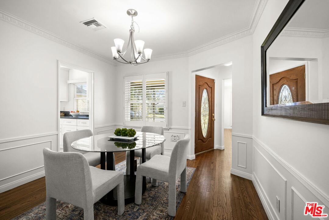 3770 Buckingham Road Los Angeles, CA 90016 - Photo 7 of 19 a dining room with wooden floor a chandelier a wooden table and chairs