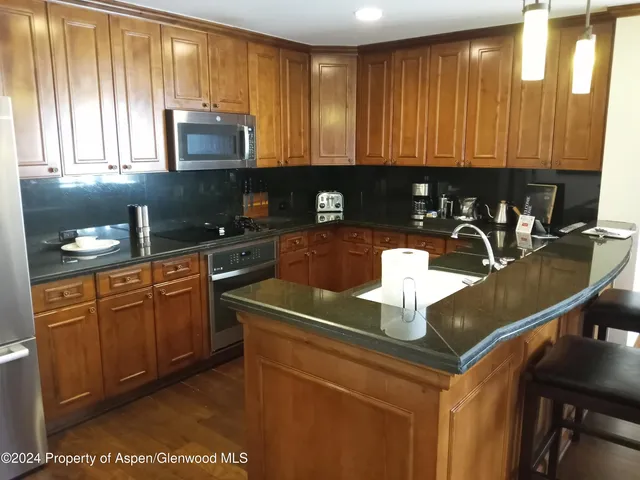 a kitchen with stainless steel appliances granite countertop a sink a stove cabinets counter space and a window