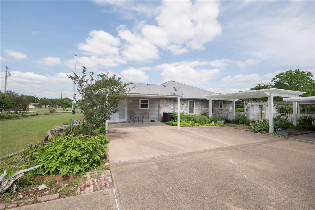 107 Fort Graham Circle Waco, TX 76705 - Photo 2 of 39 Expansive concrete driveway with attached pergola structures, a grey shingle roof, and a partial brick exterior