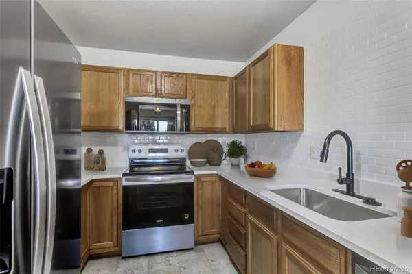 a kitchen with stainless steel appliances granite countertop a stove a sink a refrigerator and cabinets