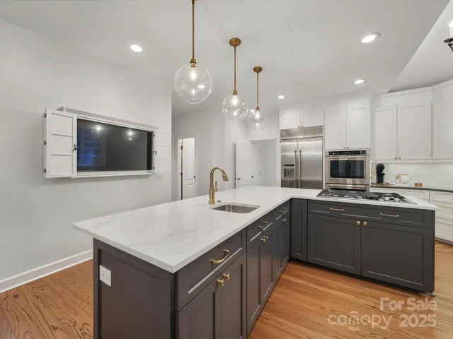 a kitchen with a sink and a stove with wooden floor