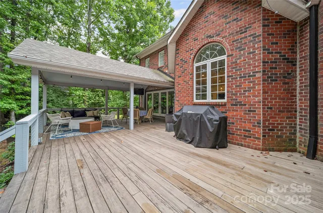 a view of a patio with table and chairs barbeque potted plants and large tree