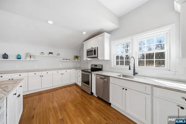 a kitchen with granite countertop white cabinets and wooden floor