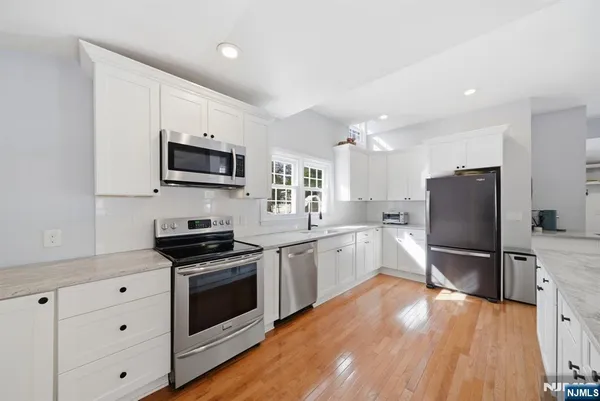 a kitchen with granite countertop a refrigerator stove top oven and sink