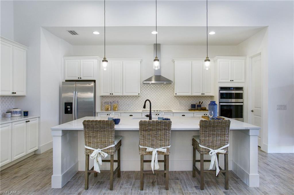 14856 Dockside Lane Naples, FL 34114 - Photo 8 of 50 a kitchen with stainless steel appliances granite countertop a table chairs refrigerator and sink