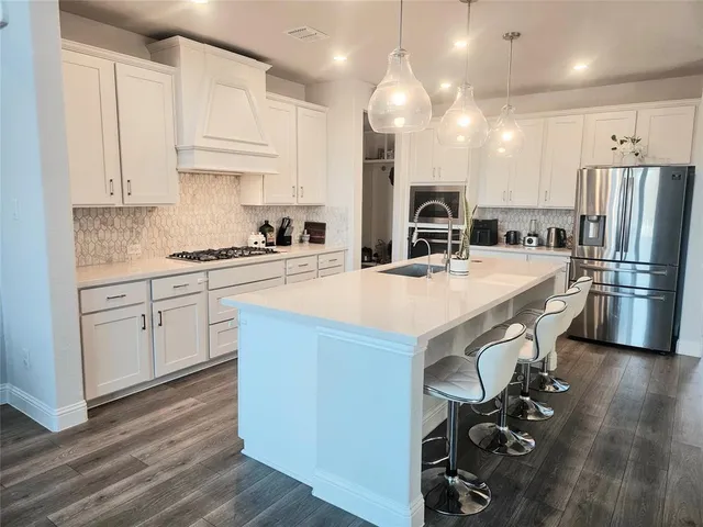 a kitchen with kitchen island a counter top space a sink stainless steel appliances and cabinets