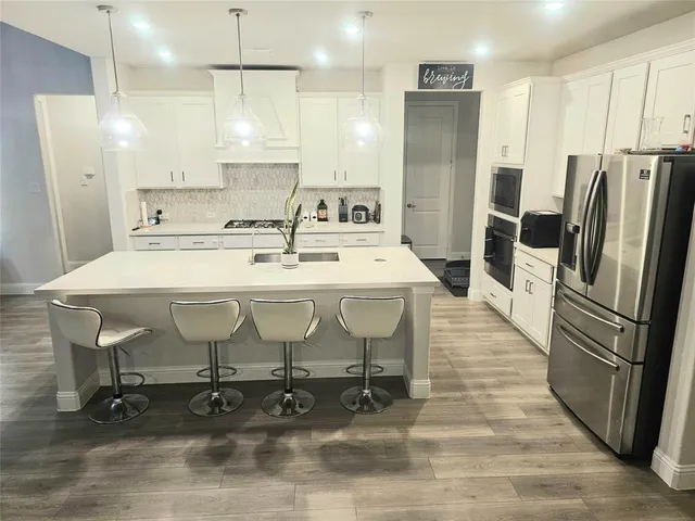 a large kitchen with stainless steel appliances a stove a sink a refrigerator and a wooden cabinets