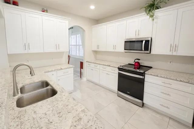 a kitchen with granite countertop a sink a stove and cabinets