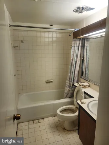 a white bath tub sitting next to a white cabinet and a stove