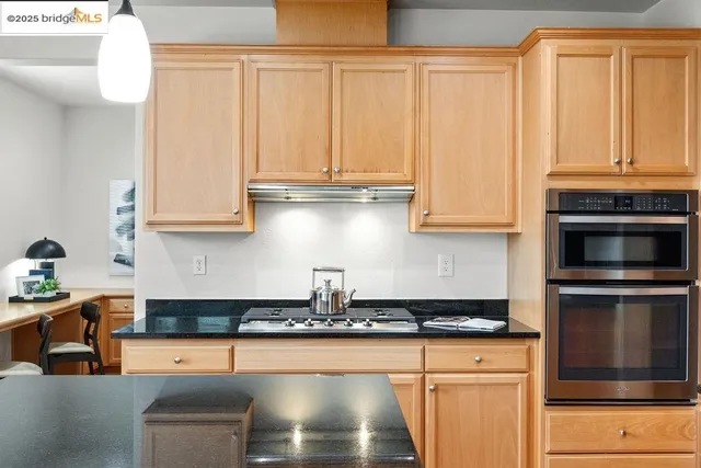 a kitchen with stainless steel appliances granite countertop a stove a sink and white cabinets