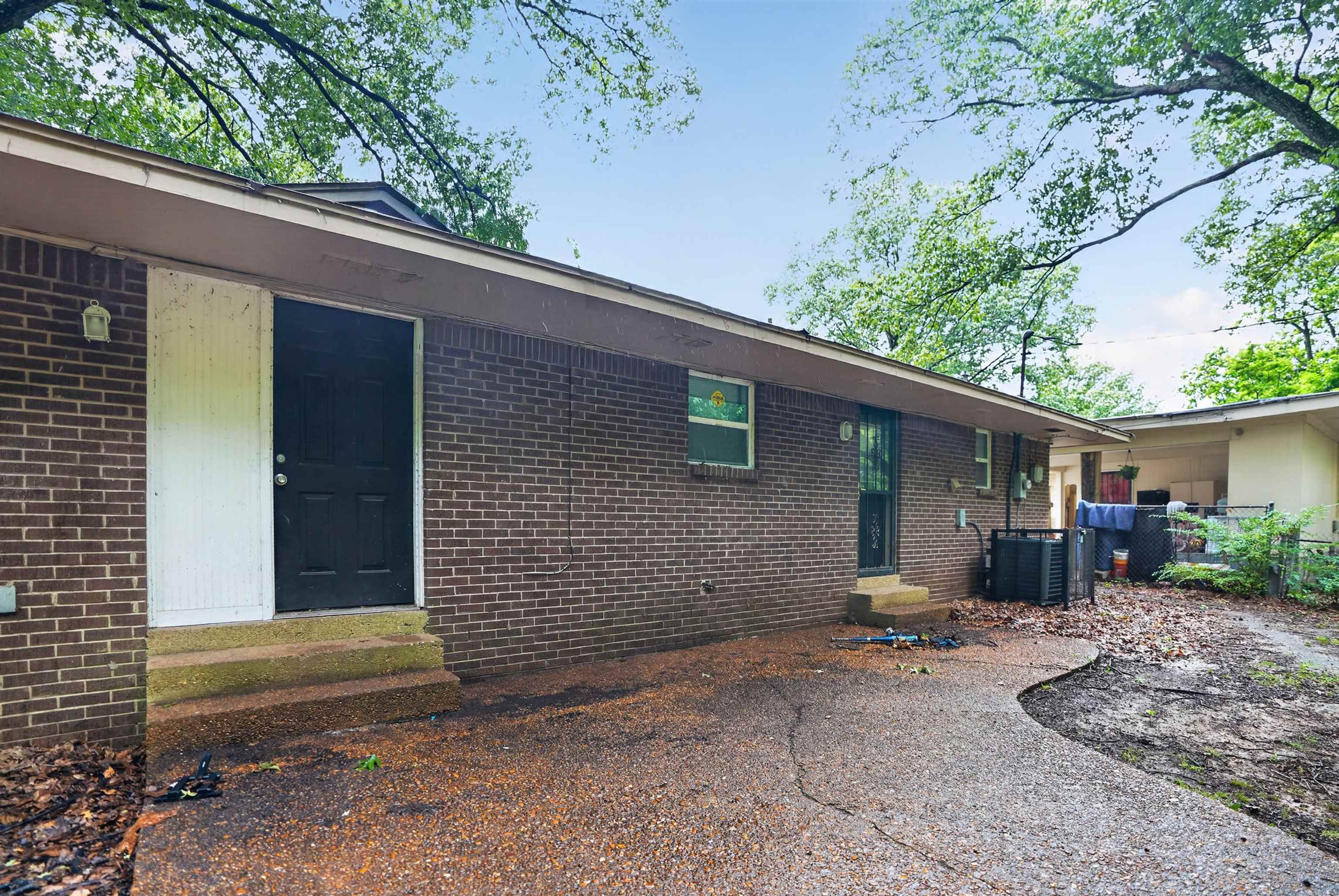1890 Pennel Road Memphis, TN 38116 - Photo 4 of 25 Brick exterior with a textured concrete patio and mature tree canopy