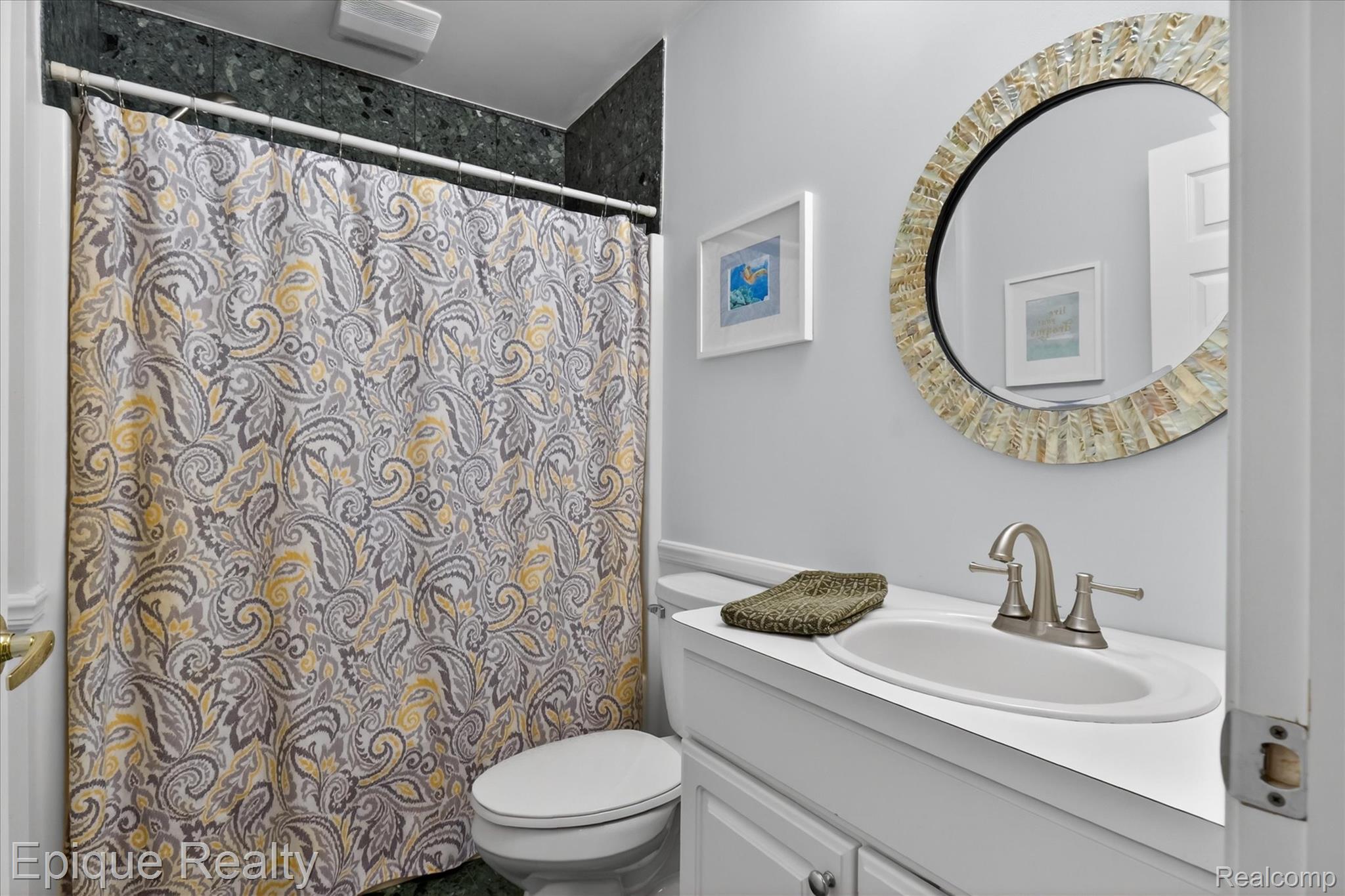 760 Caribou Court Rochester, MI 48307 - Photo 31 of 67 Bathroom featuring a white vanity with an integrated sink, brushed nickel faucet, and a round wall mirror with a decorative frame