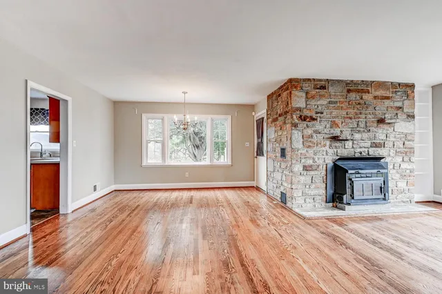 an empty room with wooden floor fireplace and windows