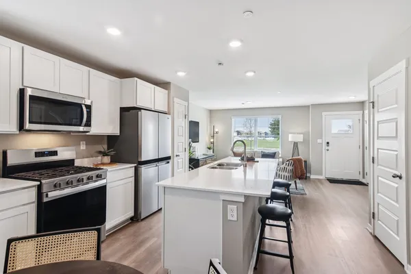 a kitchen with sink a refrigerator and chairs