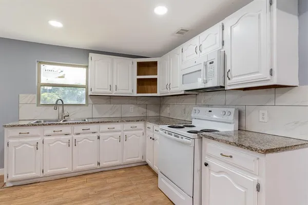 a kitchen with granite countertop white cabinets and sink