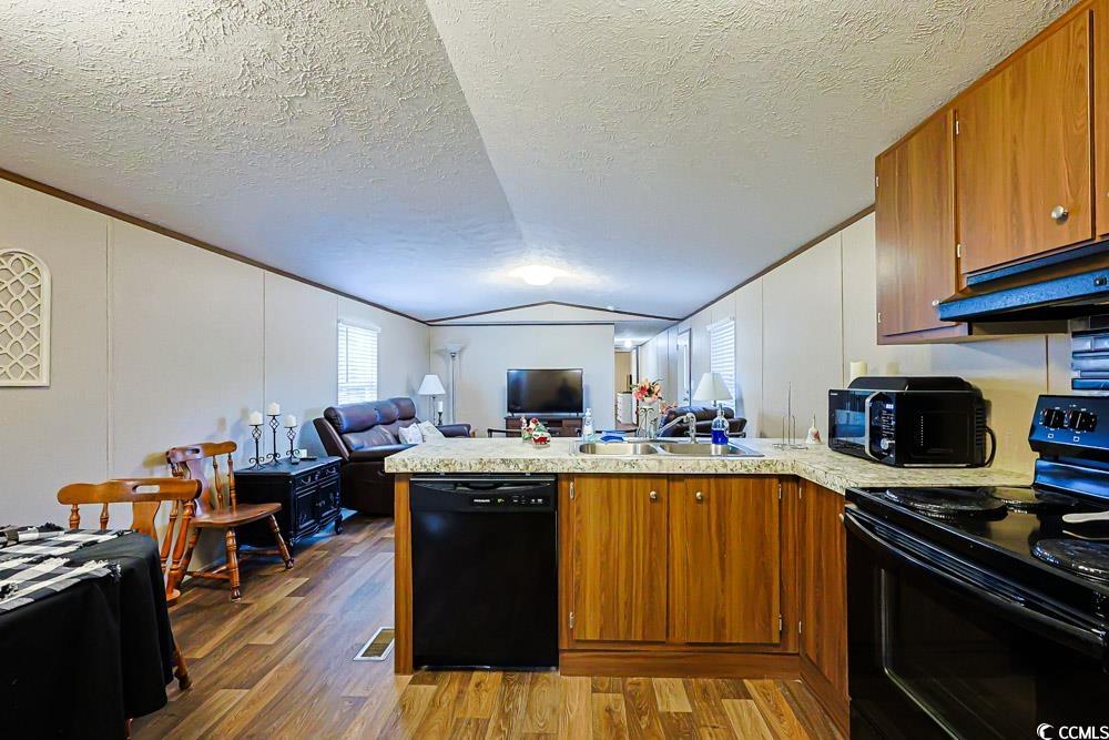 255 Quail Run Road Loris, SC 29569 - Photo 29 of 29 Kitchen featuring open floor plan, black appliances, a peninsula, brown cabinetry, and a textured ceiling