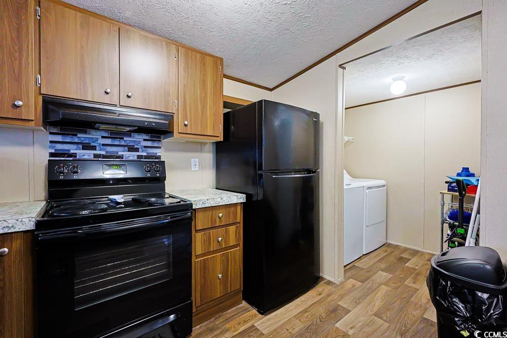 255 Quail Run Road Loris, SC 29569 - Photo 7 of 29 Kitchen with black appliances, light countertops, light wood finished floors, separate washer and dryer, and a textured ceiling