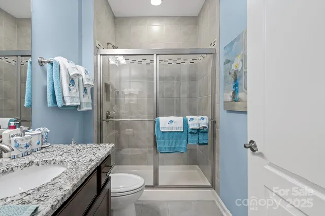 a bathroom with a granite countertop sink a toilet and shower