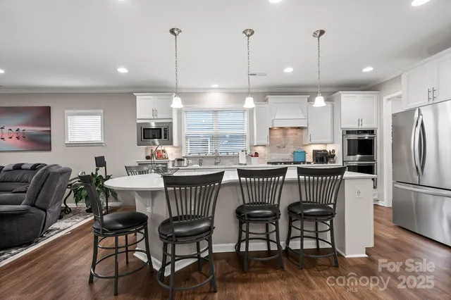 a kitchen with stainless steel appliances granite countertop a kitchen island a table and chairs