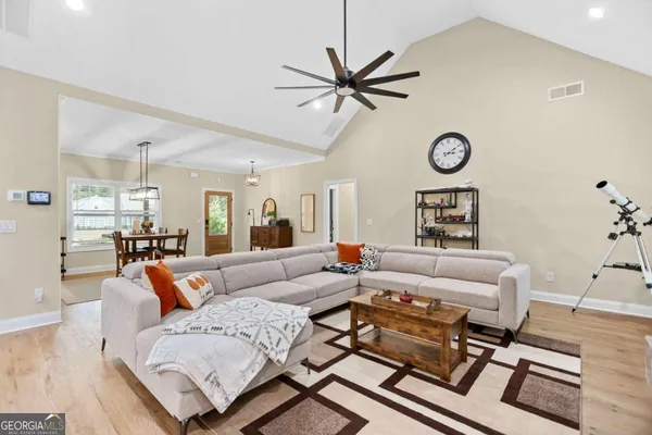 a kitchen with stainless steel appliances kitchen island granite countertop a dining table chairs and white cabinets