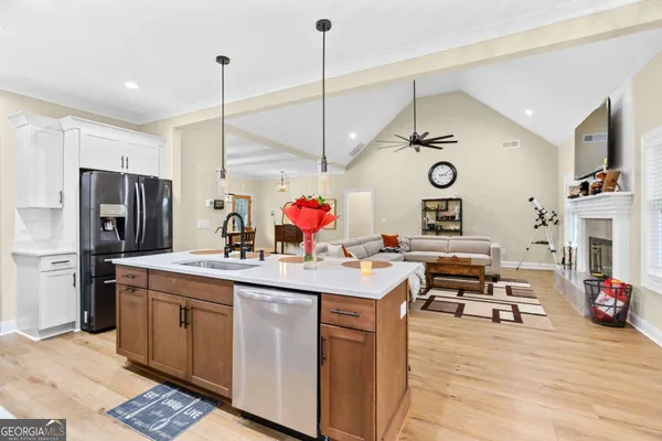 a kitchen with stainless steel appliances a white stove top oven a sink dishwasher and white cabinets with wooden floor
