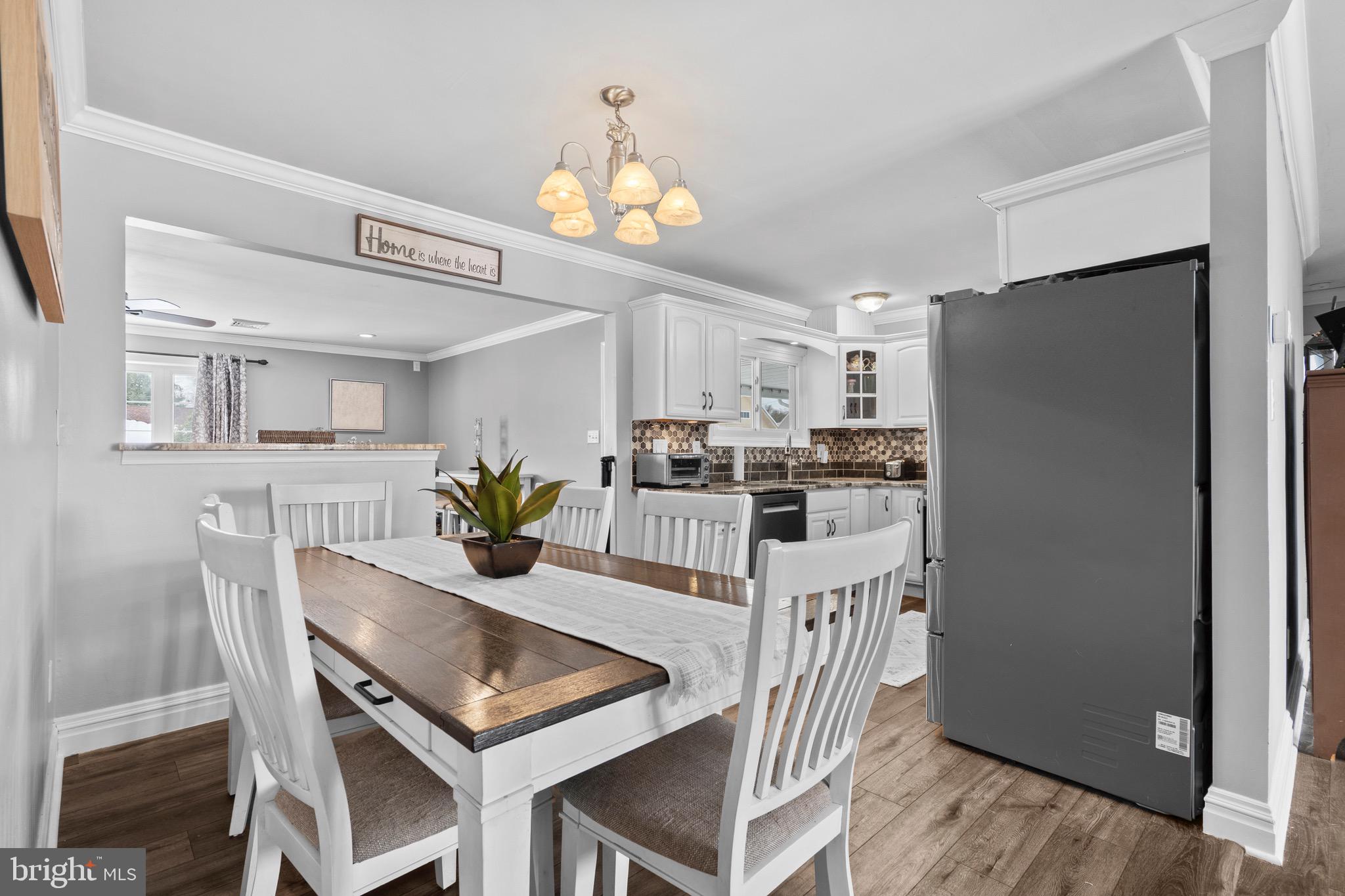 9 Honey Locust Road Levittown, PA 19056 - Photo 6 of 34 a kitchen with stainless steel appliances kitchen island granite countertop a refrigerator a stove a microwave oven a dining table and chairs with wooden floor