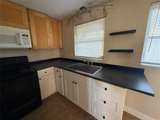 a kitchen with granite countertop white cabinets sink and window