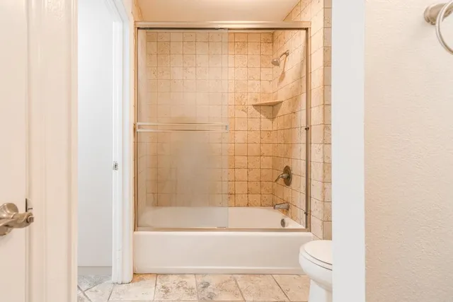 a bathroom with a granite countertop toilet a sink and shower