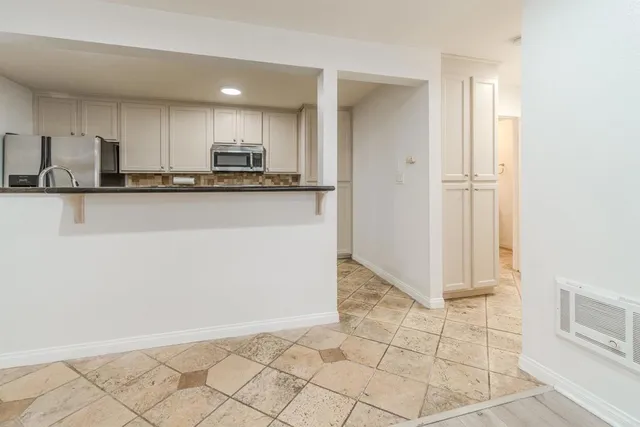 a view of kitchen with granite countertop cabinets and refrigerator