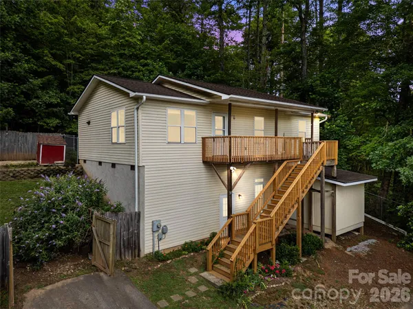 a side view of a house with a yard and potted plants