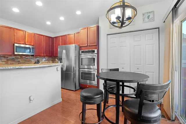 a kitchen with stainless steel appliances granite countertop a kitchen island a stove a table and chairs