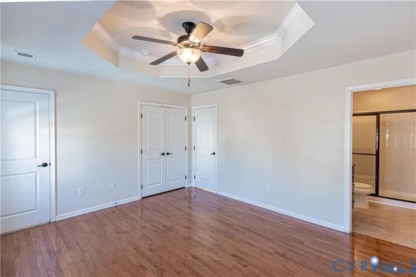 an empty room with wooden floor chandelier fan and closet area with wooden floor