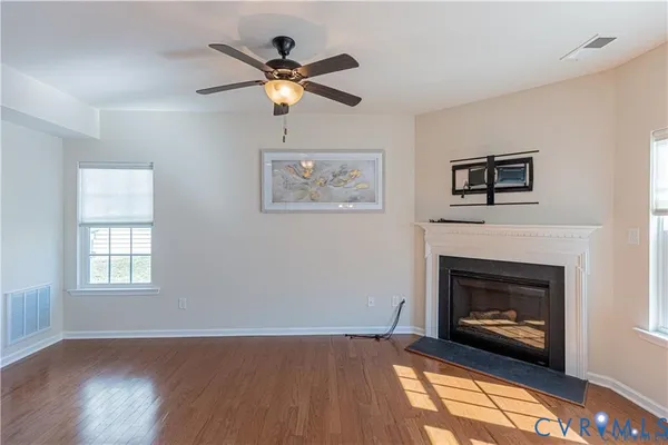 a view of a livingroom with a fireplace a ceiling fan and wooden floor