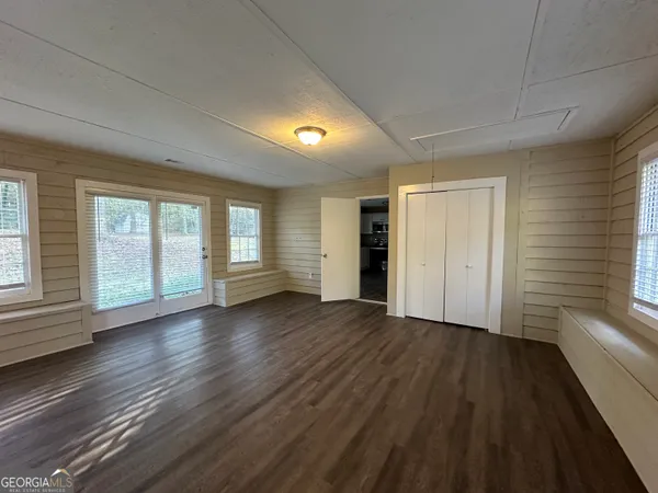 an empty room with wooden floor and windows
