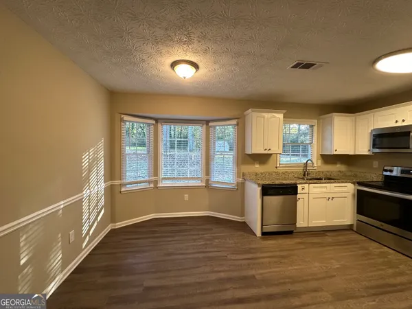 a large kitchen with stainless steel appliances granite countertop a stove and a large window